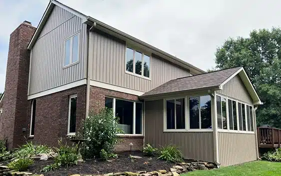 rear view of home with tan siding and brick